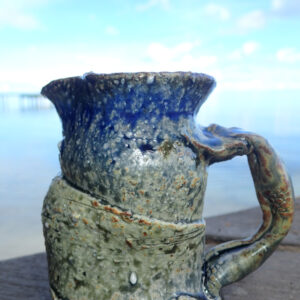This medium small pitcher is hand thrown on the potter's wheel and slighty altered with a sculpted Japanese style handle. It is made with stoneware or Japanese style clay and glazed in blue and yellow Huahine lagoon glaze. Each picture is unique